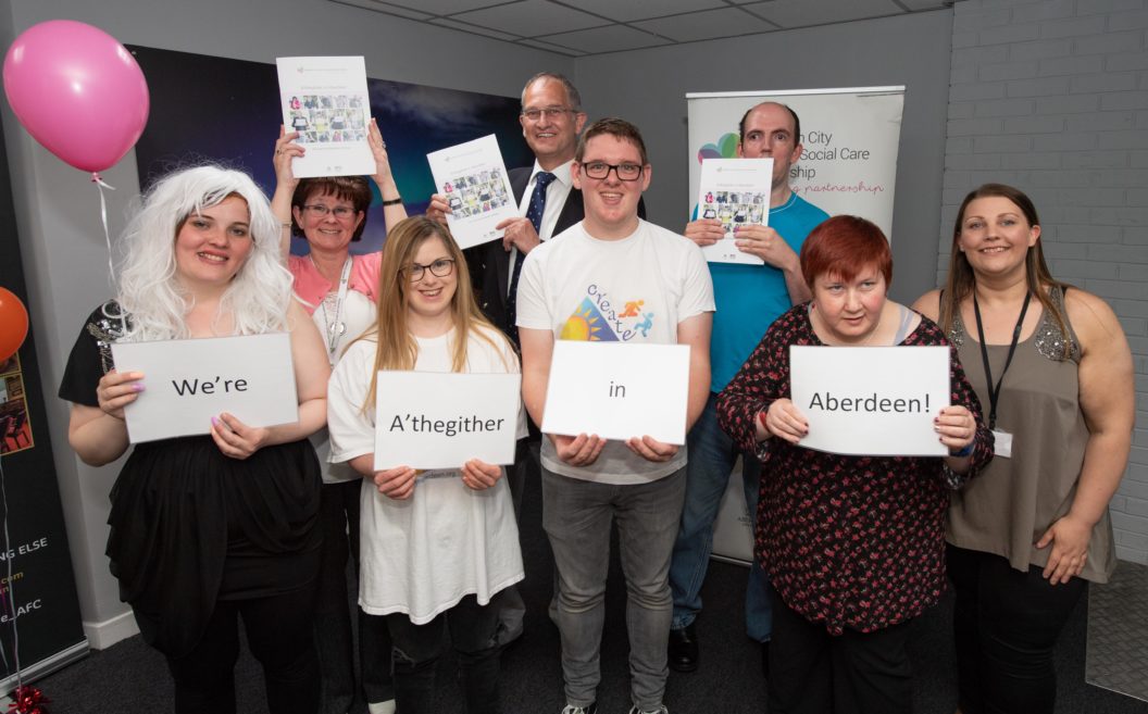 group of people smiling and holding all together in aberdeen signs