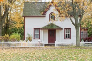 a white wooden house surrounded by autumn leaves