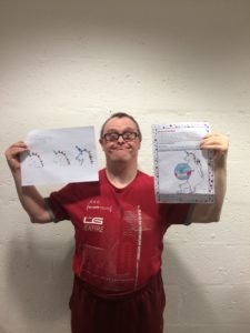 competition winner Stephen Dickson holds up his original unicorn drawing and the unicorn mascot design and smiles