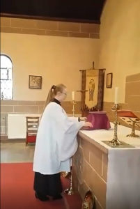 Leeanne stands in front of the altar in her church robes and lays out items for the service