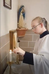 Leeanne lights a candle in the church, dressed in her robes