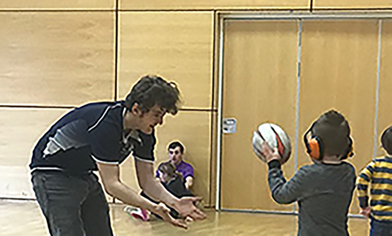 Stephen plays rugby with a child with learning disabilities in a sports hall