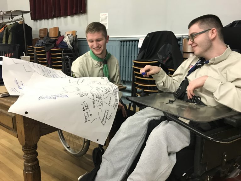 Michael and Ross sit in their scouting uniforms and plan out what community means to them on a sheet of A3 paper