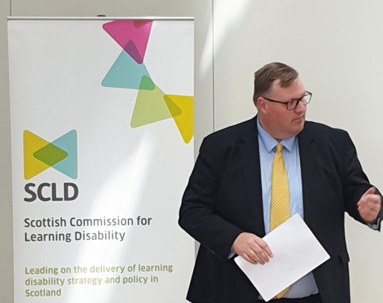 Councillor Currie stands in front of an SCLD banner to launch the local strategy guidance