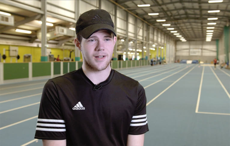 Award winner Lewis McDermid talks in front of an indoor athletics track