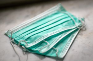 Three green disposable face masks lie on a white surface