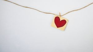 A picture of heart on a piece of string against a white wall. Photo credit: Debby Hudson on Unsplash.