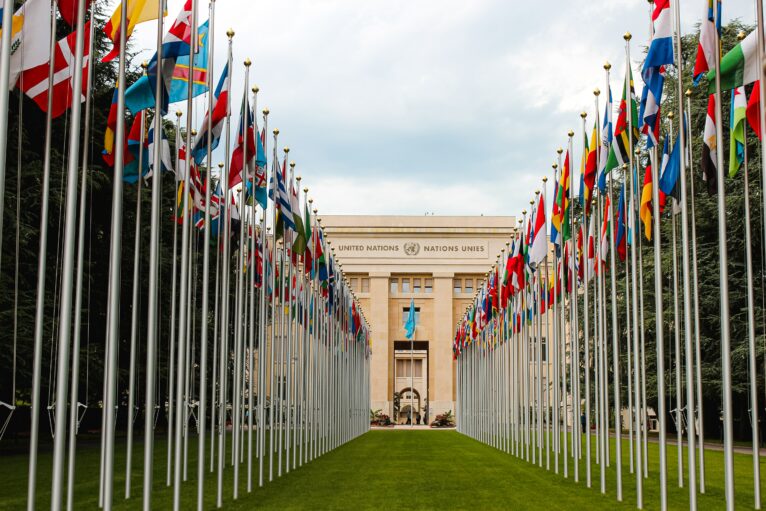 A view of the front of the UN headquarters in Geneva, seen through the flags of different nations. Photo credit: Mat Reding on Unsplash