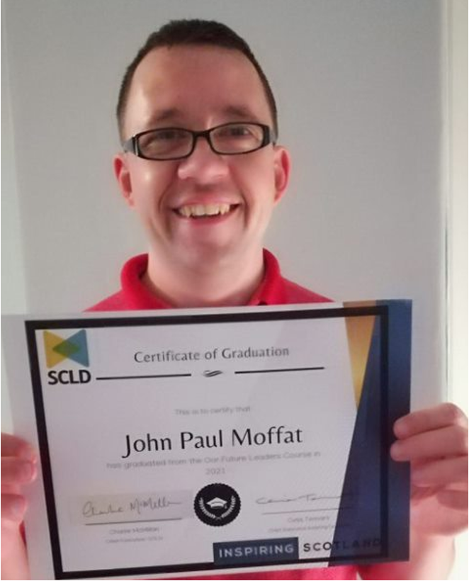 John Paul Moffat holding his certificate of graduation
