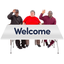 Image of three people sitting behind a desk which says "welcome"